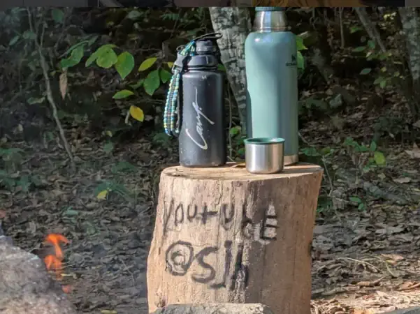 coffee thermos on a log in a campground